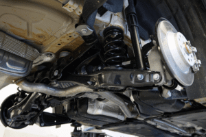 Brake and strut safety, auto repair in Racine, WI at Durand Automotive. Image of a vehicle undercarriage showing the coil spring, shock absorber, control arm, and brake rotor during inspection.