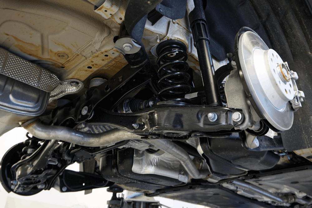 Brake and strut safety, auto repair in Racine, WI at Durand Automotive. Image of a vehicle undercarriage showing the coil spring, shock absorber, control arm, and brake rotor during inspection.